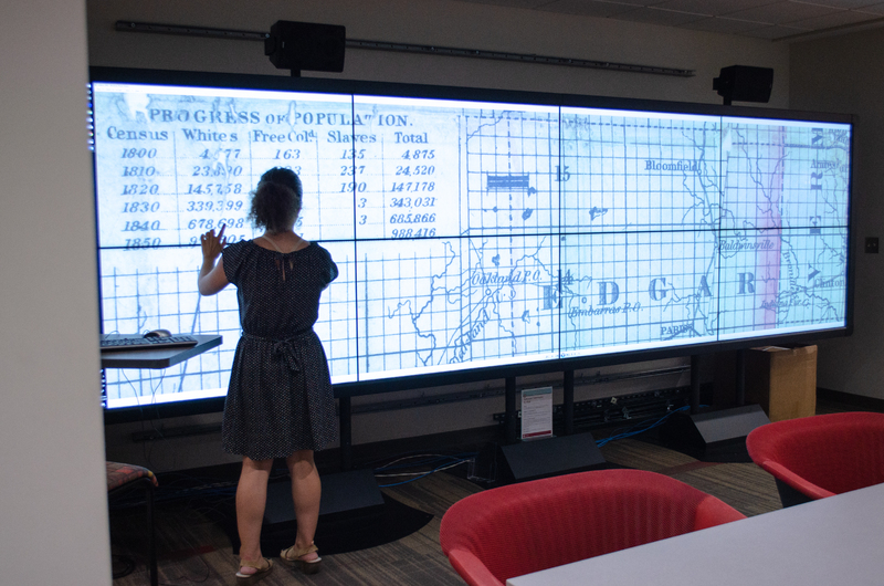 Wells Library Touchscreen IQ Wall with black and white map on screen with woman standing in front.